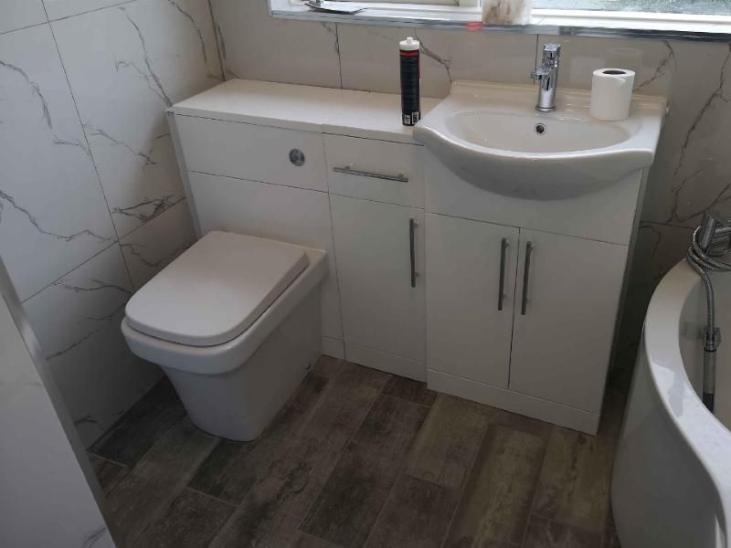 Marble-effect tiled bathroom with white vanity unit